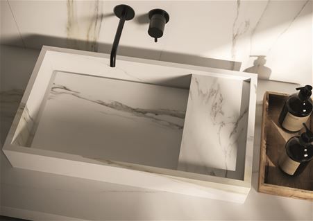 Modern custom-made washbasin in Calacatta Gold ceramic with concealed drain. Combined with a coating of the same material.