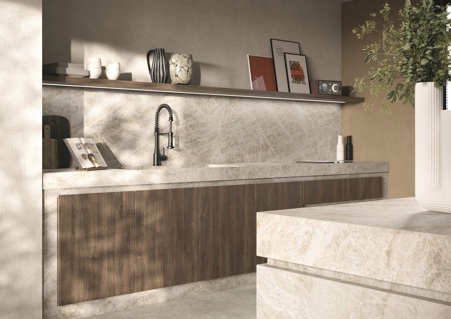 Cucina dalle tonalità calde con struttura, rivestimento, isola e top in gres porcellanato Yamuna matte e lavello assemblato integrato al top. Il gres Yamuna matte grazie alla sua tonalità chiara di grigio e alle sue venature beige aiuta ad armonizzare il contrasto tra la pavimentazione in ceramica Fossil Gray matte e le ante in legno scuro della cucina.