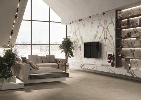 Modern living room with warm and bright colors. To achieve this, the floor was made in Fossil Ivory matte. Instead, the cladding of the living room, the back of the shelving and the floating furniture were made of Eternal gold matte porcelain stoneware. In particular, large-format slabs from the Florim Stone line and a book match laying were needed to create the cladding.