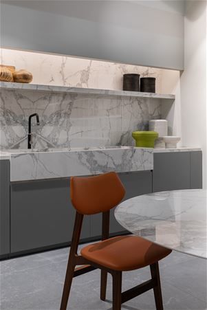 Modern kitchen with shaped tailor made table, large sink, countertop, shelf and kitchen covering in book match Marble White stoneware