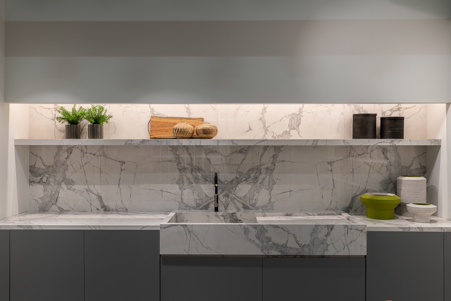 Modern kitchen composed of wide sink with assembled capacious tub, top, shelf and kitchen cladding in Marble White with book match