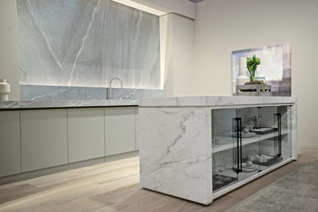 Isola cucina contenitiva adibita a piano di lavoro interamente realizzata in ceramica Marble Calacatta A matte abbinata a cucina con piano e rivestimento in Alpine Grey matte