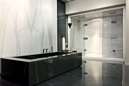 Minimal bathroom with strong contrasts with flooring and bathtub in glossy Marble Marquinia and bathroom and shower cladding in open book match Marble Calacatta Glod glossy